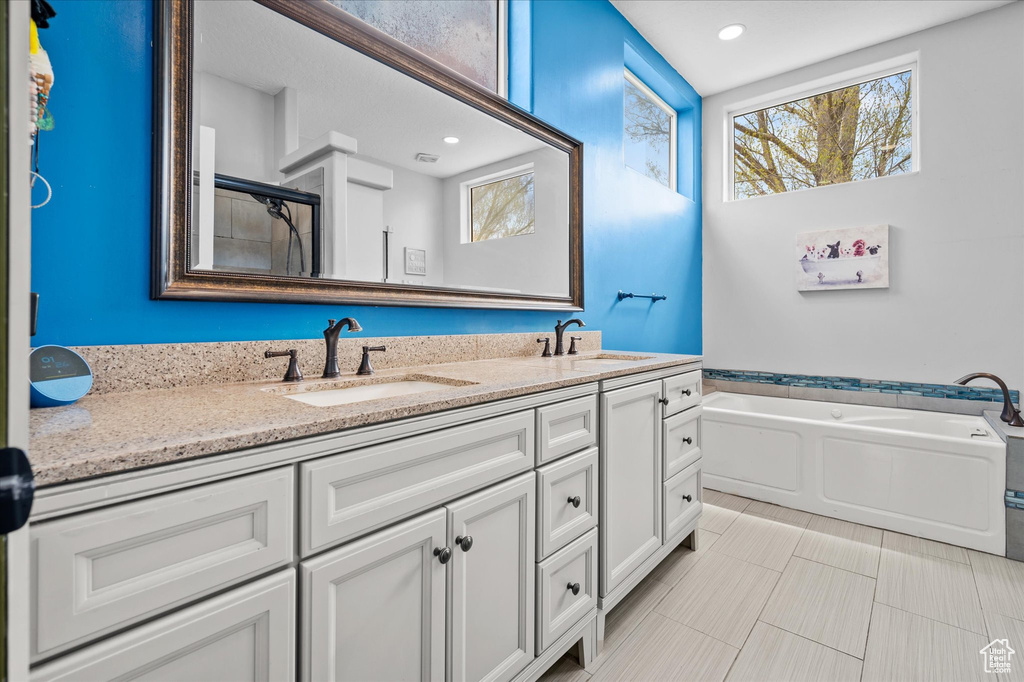 Bathroom featuring double vanity, a sink, an enclosed shower, and a garden tub