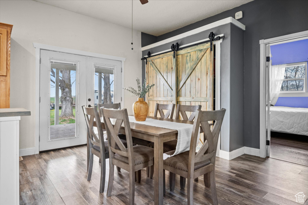 Dining space featuring french doors, baseboards, a barn door, and wood finished floors