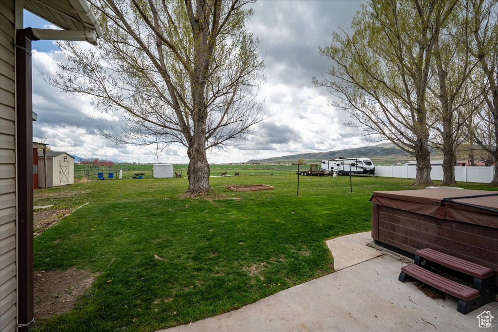 View of yard with an outdoor structure, fence, a shed, a patio area, and a hot tub