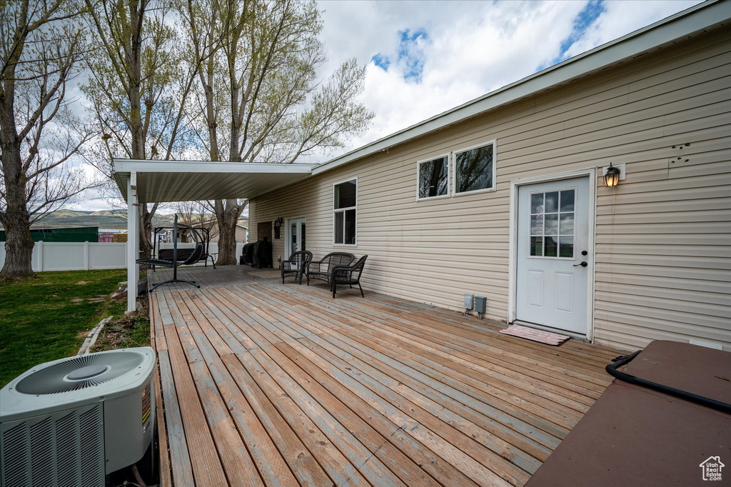 Wooden terrace with central AC unit, fence, and a yard