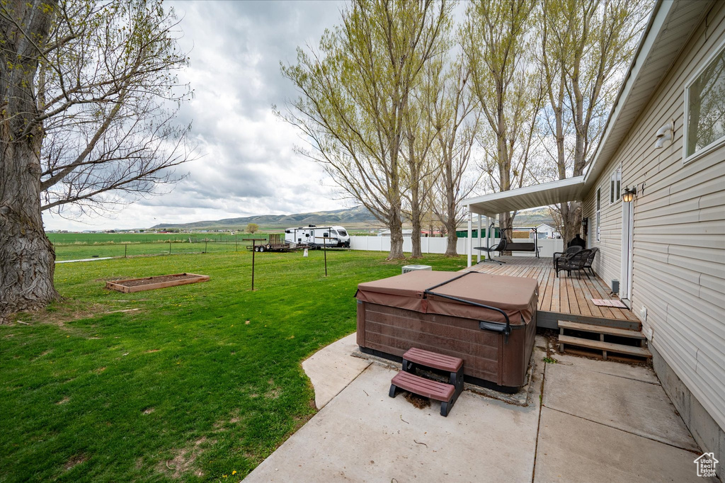 Exterior space featuring a hot tub, a deck, fence, and a patio area