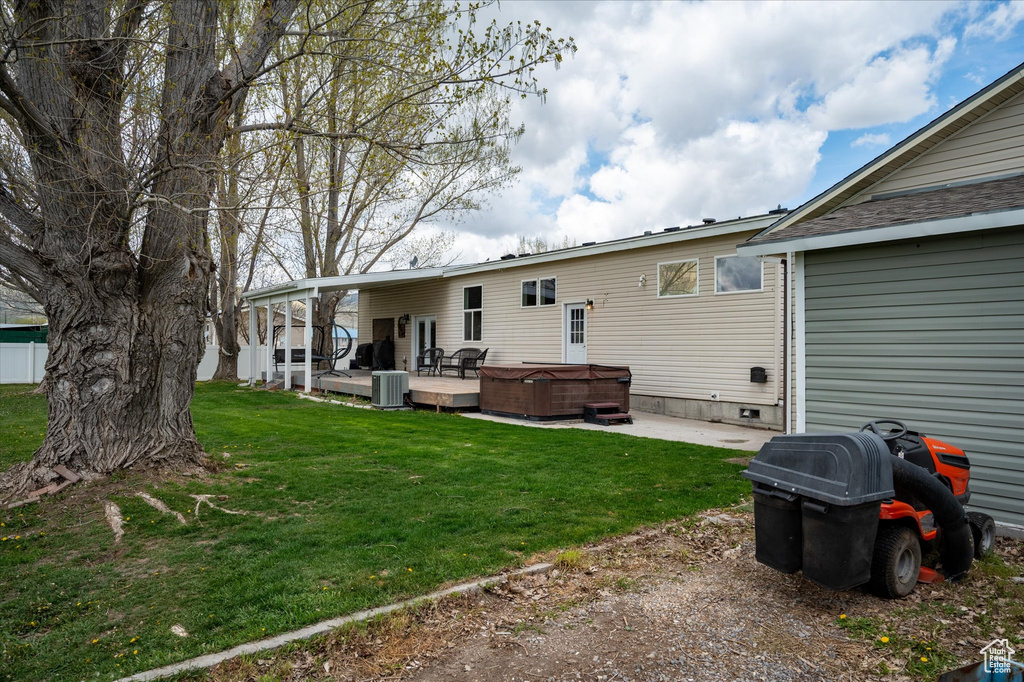 Rear view of property with central AC unit, a patio area, crawl space, a hot tub, and a yard