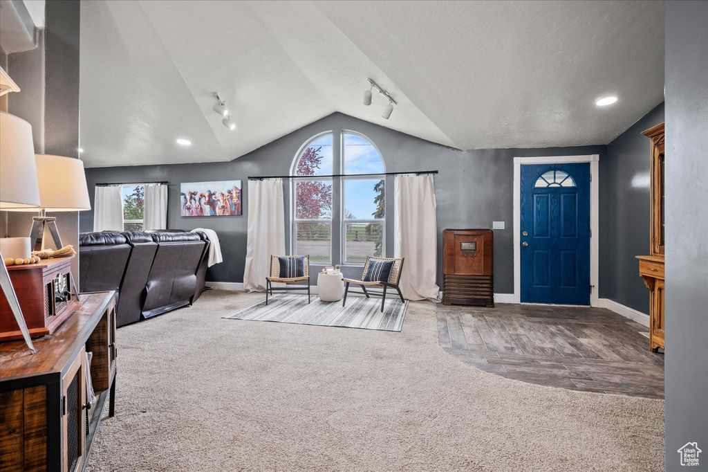 Entrance foyer with carpet flooring, baseboards, and vaulted ceiling