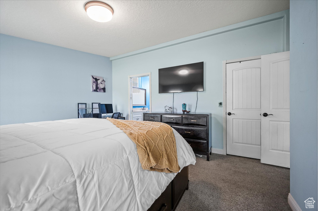 Bedroom featuring baseboards, dark carpet, and a textured ceiling