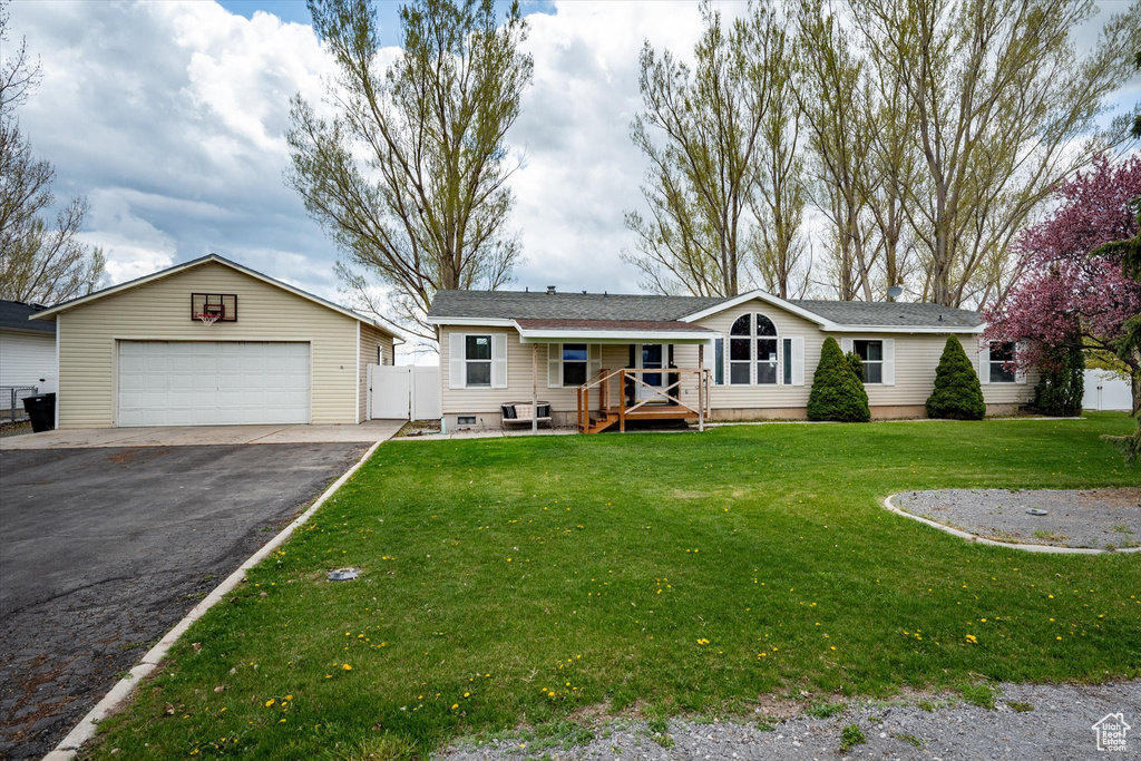 Ranch-style house with an outdoor structure, a garage, a front lawn, aphalt driveway, and fence