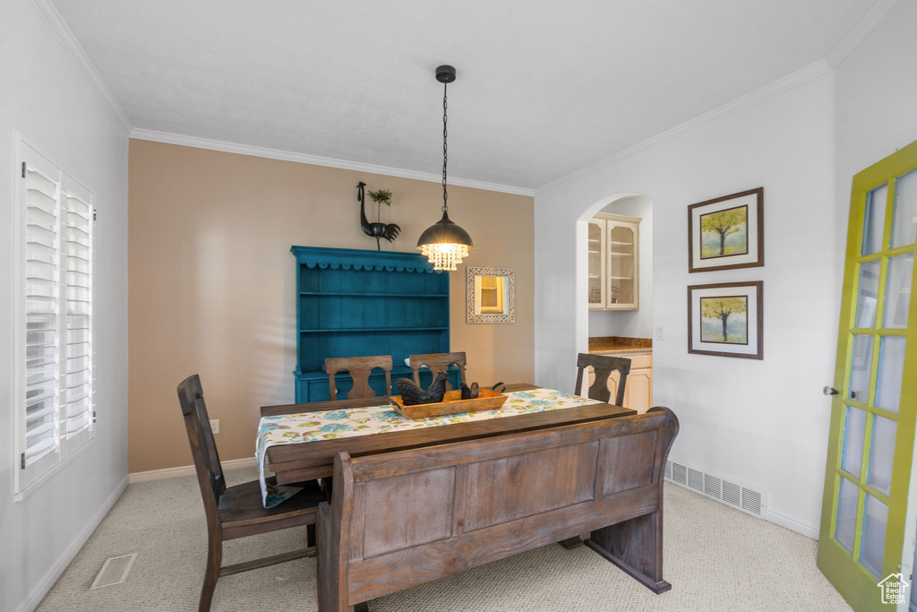 Dining space featuring crown molding, light colored carpet, baseboards, and visible vents