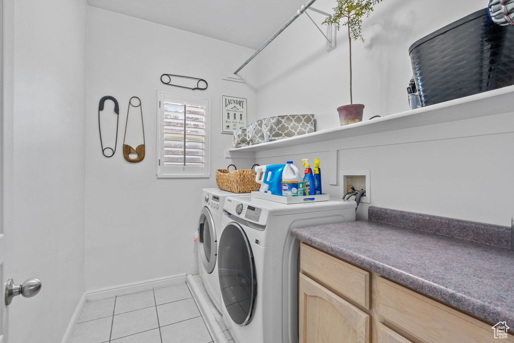 Clothes washing area with washing machine and clothes dryer, laundry area, baseboards, and light tile patterned floors