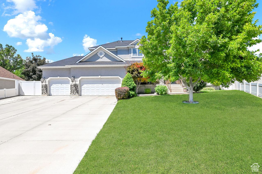 View of front of home featuring a front yard, fence, concrete driveway, an attached garage, and stucco siding