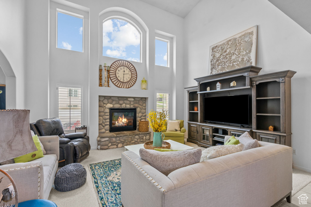 Carpeted living room featuring arched walkways, a high ceiling, baseboards, and a fireplace