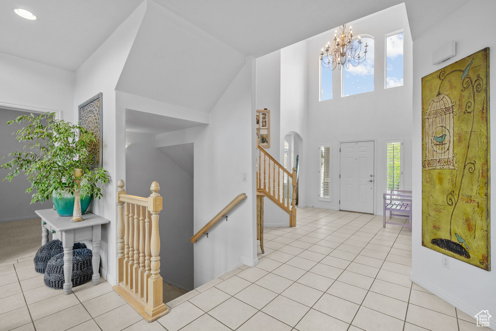 Entrance foyer featuring light tile patterned flooring, a notable chandelier, recessed lighting, baseboards, and a towering ceiling