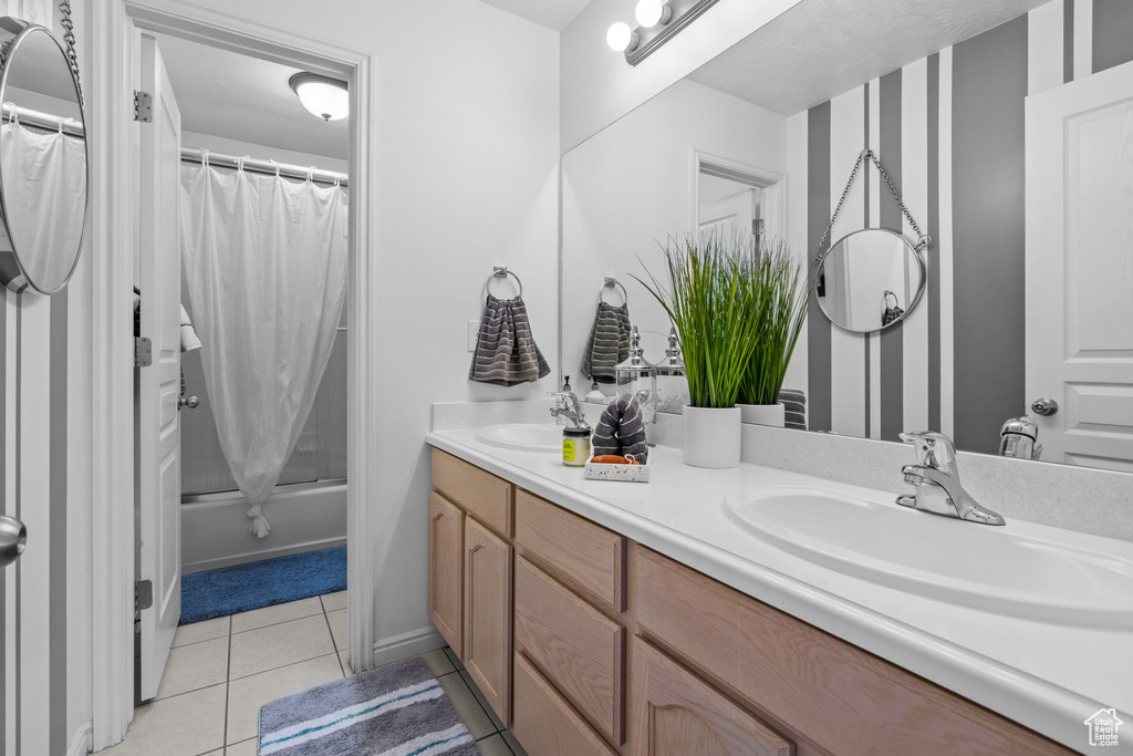 Full bath featuring double vanity, a sink, tile patterned floors, and shower / tub combo with curtain