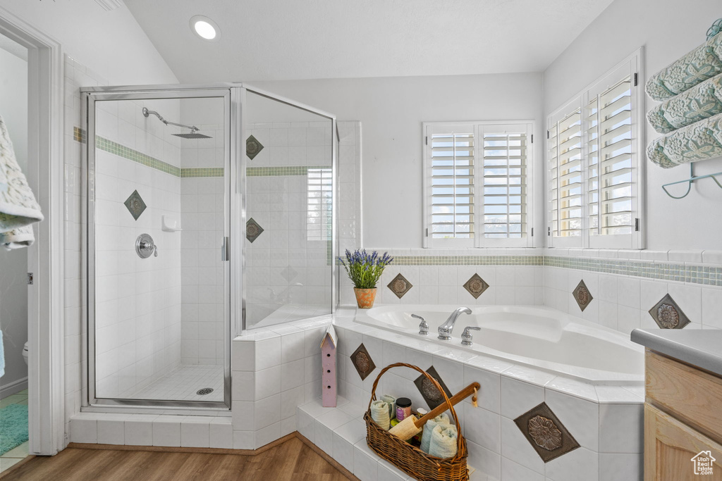 Bathroom with wood finished floors, a bath, a stall shower, and vanity