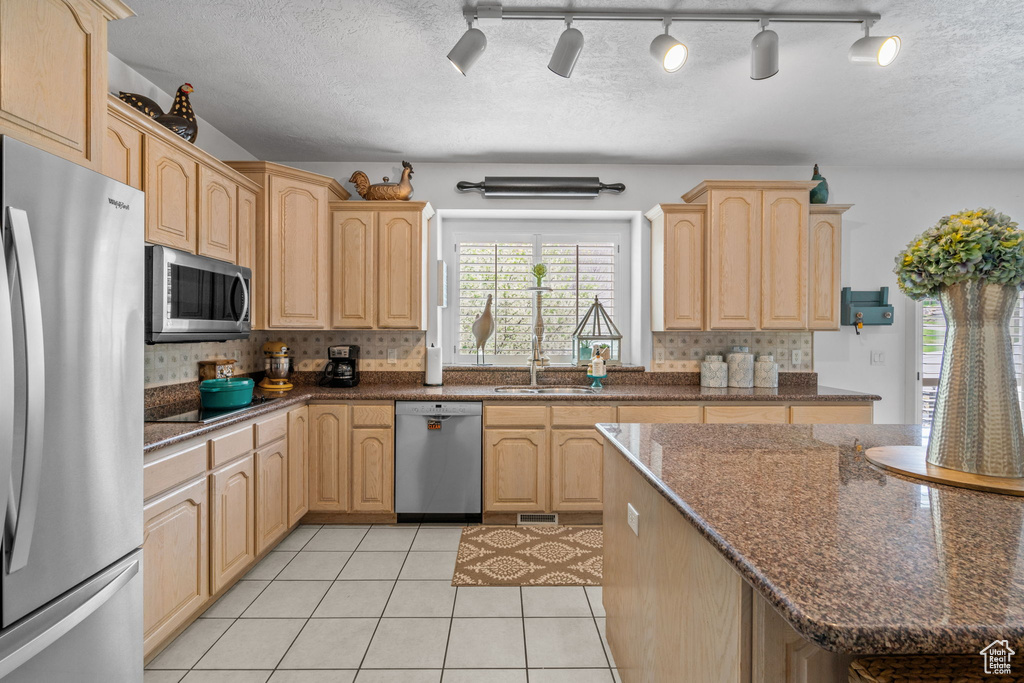 Kitchen featuring decorative backsplash, light brown cabinets, a sink, appliances with stainless steel finishes, and light tile patterned floors