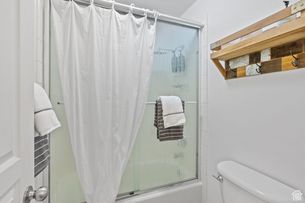 Bathroom with combined bath / shower with glass door and toilet