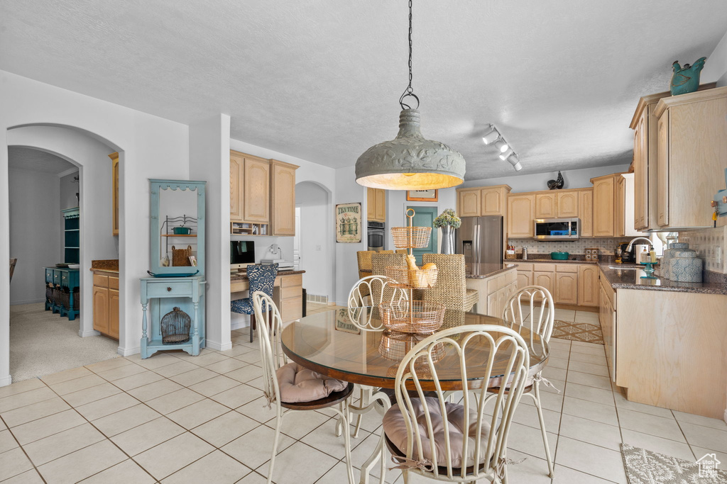 Dining area with arched walkways, a textured ceiling, and light tile patterned flooring