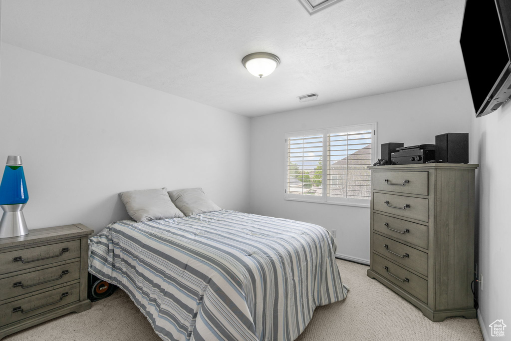Bedroom featuring light colored carpet and visible vents