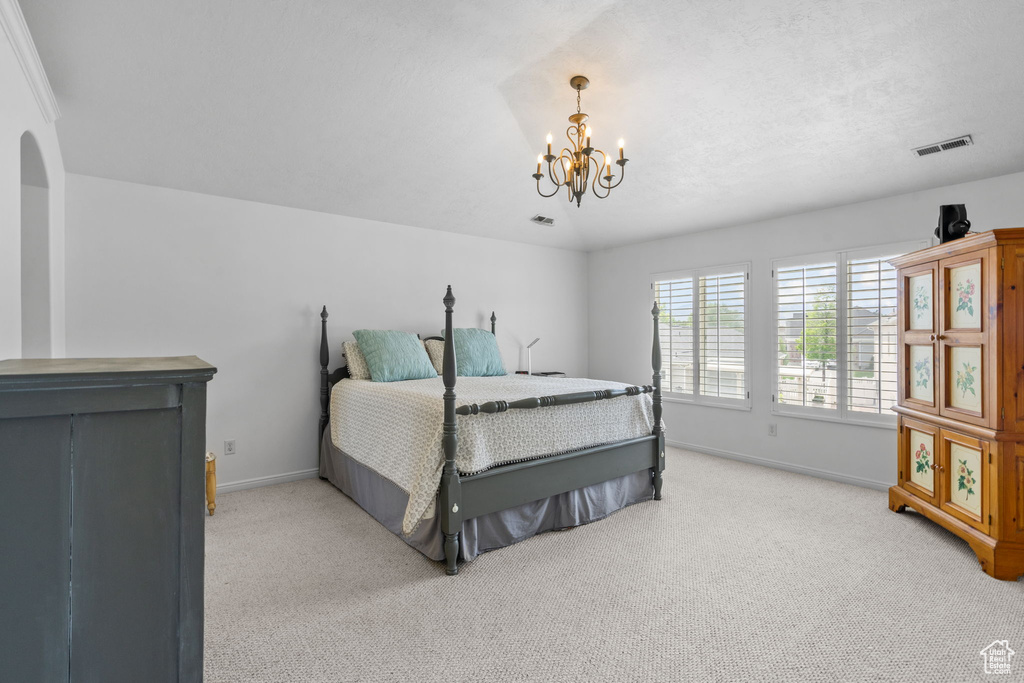Bedroom with baseboards, visible vents, a chandelier, and light colored carpet