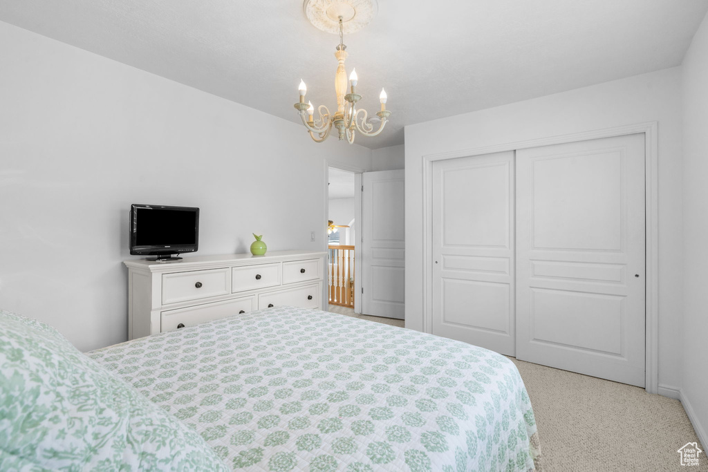 Bedroom with baseboards, a chandelier, light carpet, and a closet