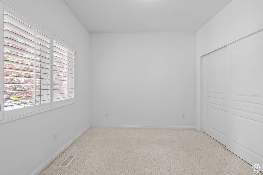 Unfurnished bedroom featuring carpet floors, visible vents, and multiple windows