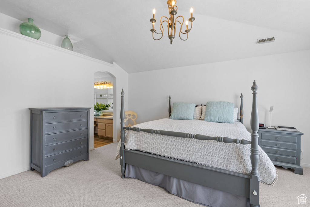Carpeted bedroom featuring connected bathroom, arched walkways, a chandelier, lofted ceiling, and visible vents