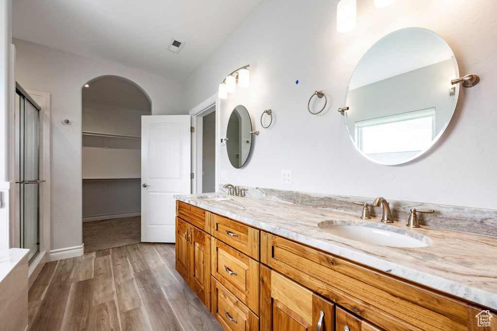 Full bath featuring double vanity, visible vents, a shower stall, wood finished floors, and a sink