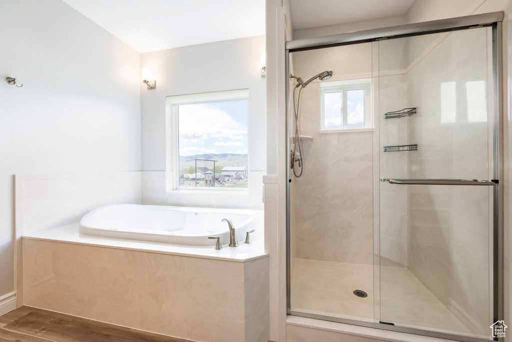 Full bath featuring a stall shower, a bath, and wood finished floors