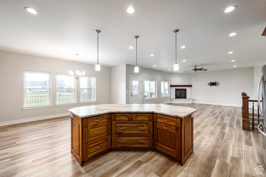 Kitchen featuring recessed lighting, open floor plan, a glass covered fireplace, and light wood-style flooring