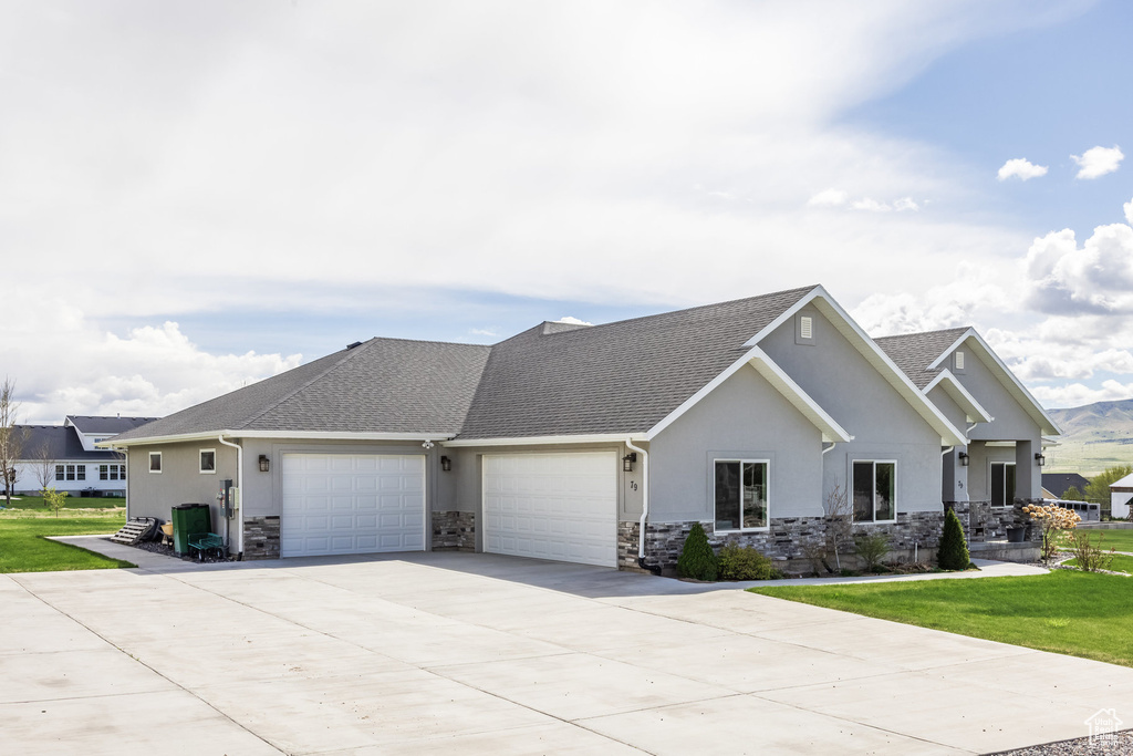 View of front of property with concrete driveway, a garage, stone siding, and stucco siding