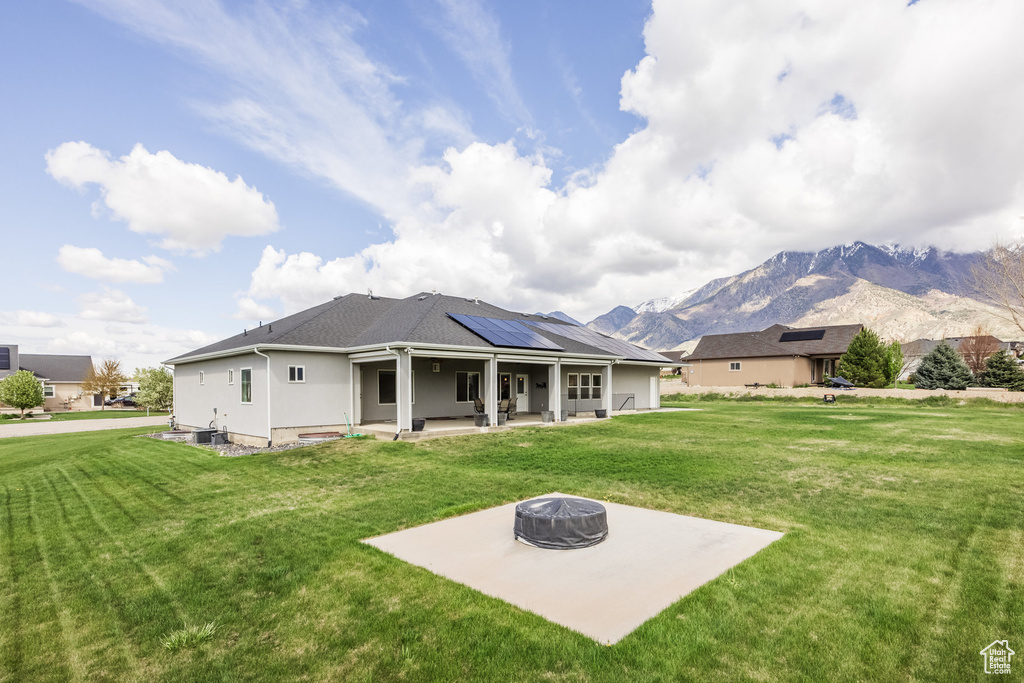 Rear view of house with a patio, stucco siding, an outdoor fire pit, a mountain view, and a yard