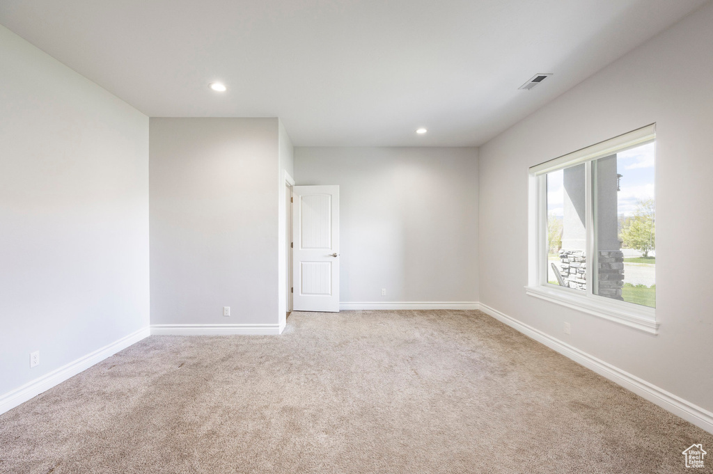 Empty room with visible vents, recessed lighting, baseboards, and light carpet