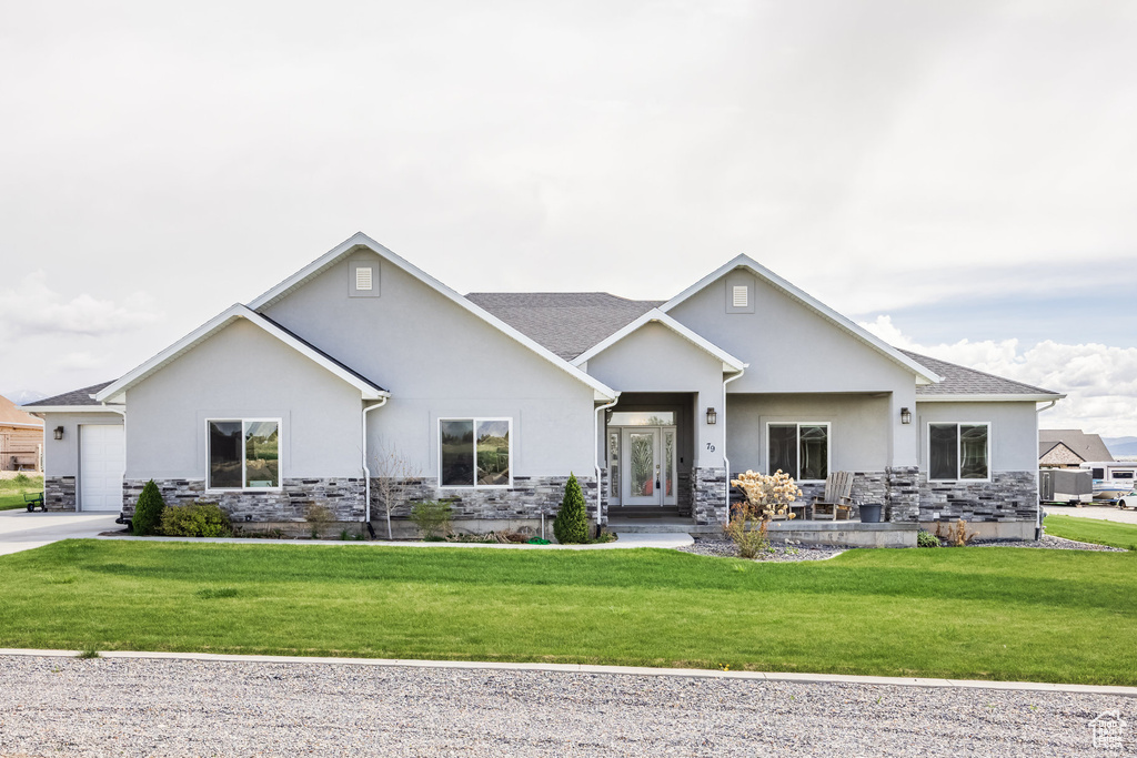 View of front of home with stucco siding, a front yard, and stone siding