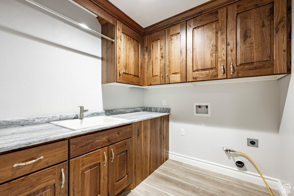 Washroom featuring hookup for a washing machine, light wood-type flooring, electric dryer hookup, a sink, and cabinet space