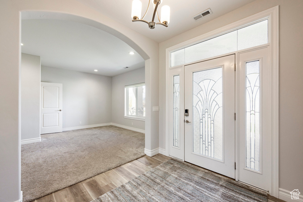 Entryway with visible vents, an inviting chandelier, wood finished floors, baseboards, and arched walkways