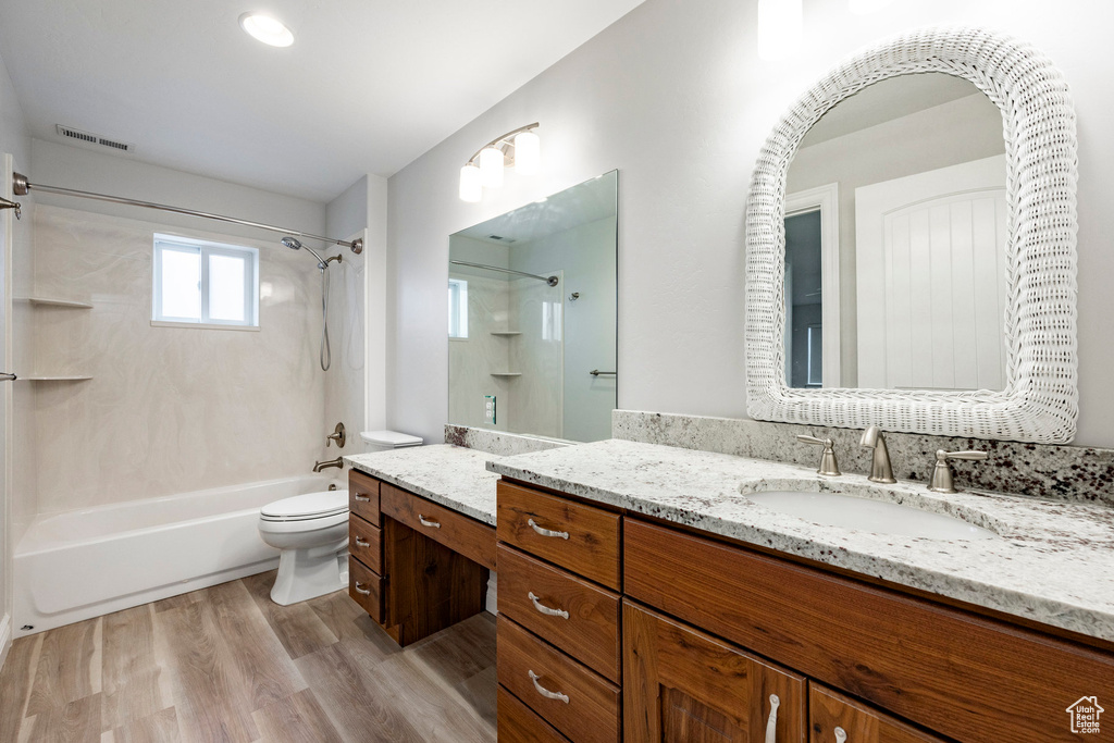 Bathroom with vanity, toilet, shower / bath combination, wood finished floors, and visible vents