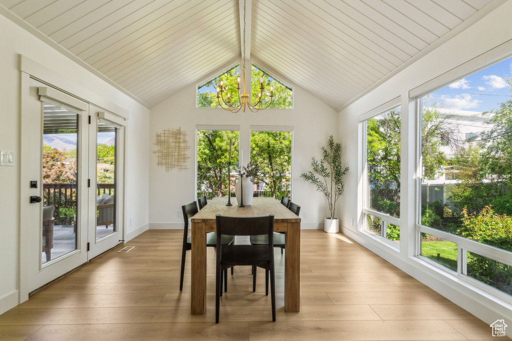Sunroom with a chandelier, french doors, lofted ceiling, and wood finished floors
