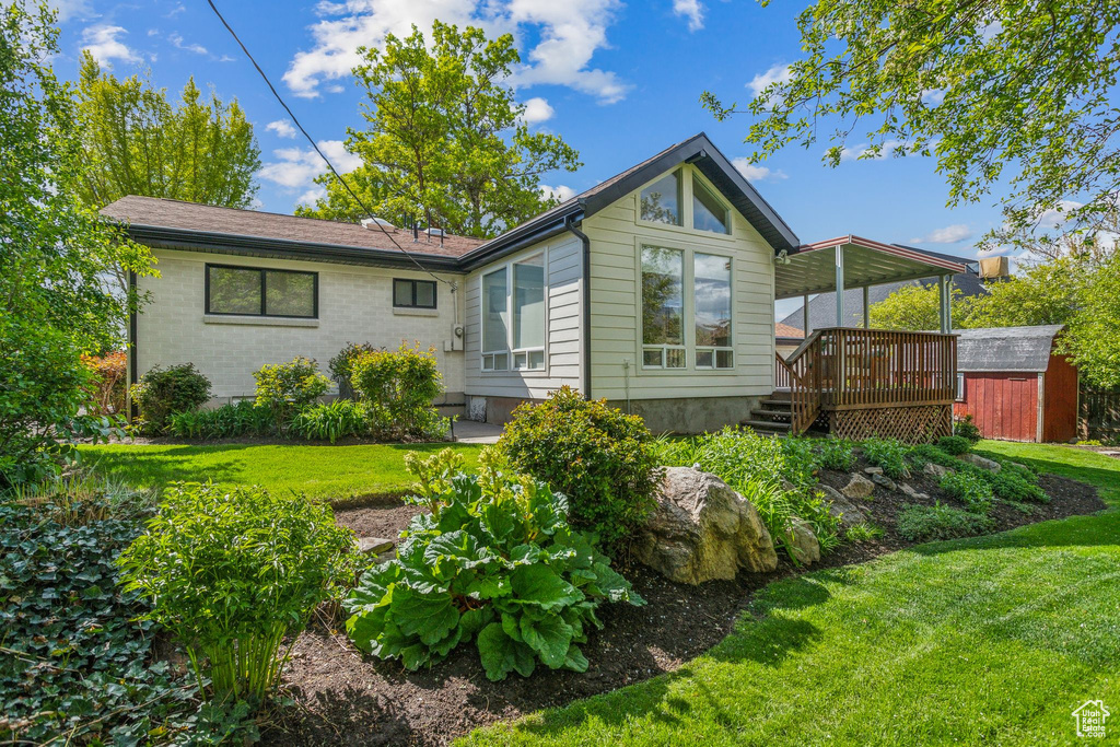 Back of property featuring a shed, an outdoor structure, a yard, and a deck