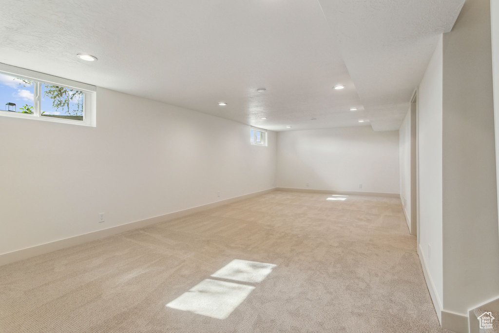 Basement with a wealth of natural light, recessed lighting, and light colored carpet