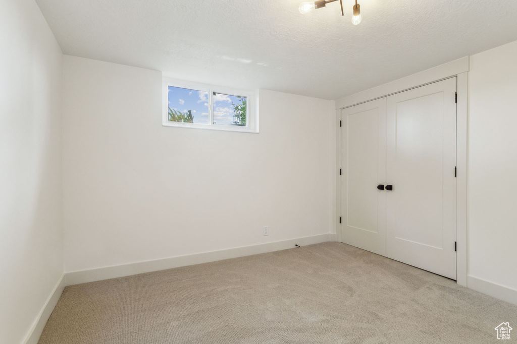 Interior space with baseboards, a closet, and light carpet