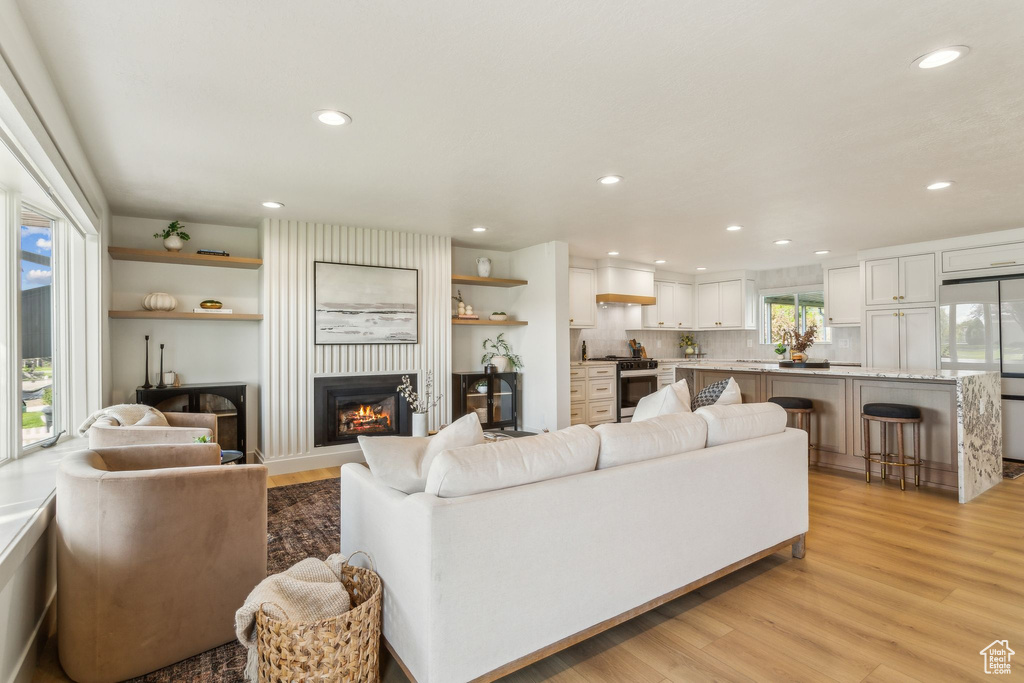Living room with recessed lighting, light wood-style flooring, and a fireplace