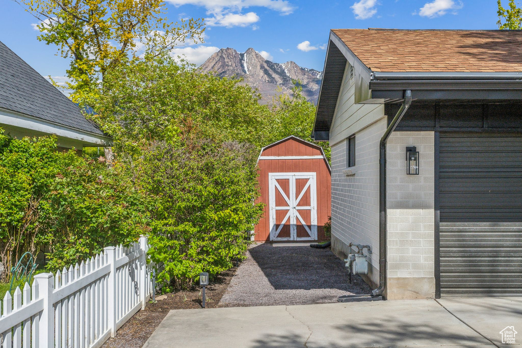 Exterior space with a shingled roof, concrete block siding, a mountain view, and fence