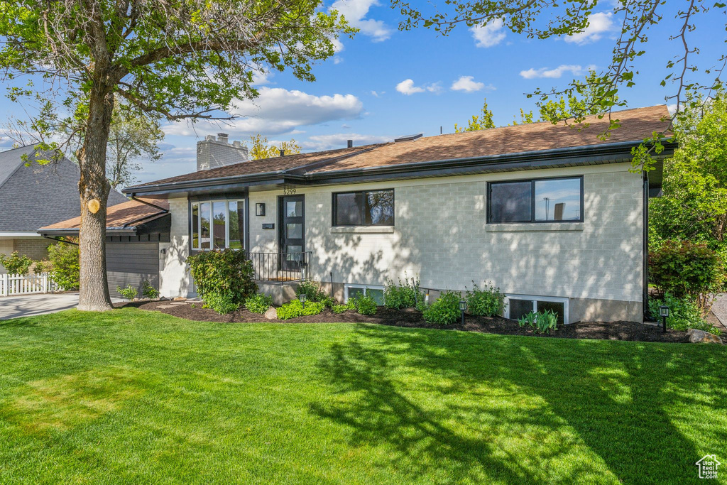 Ranch-style house featuring a chimney, driveway, and a front lawn