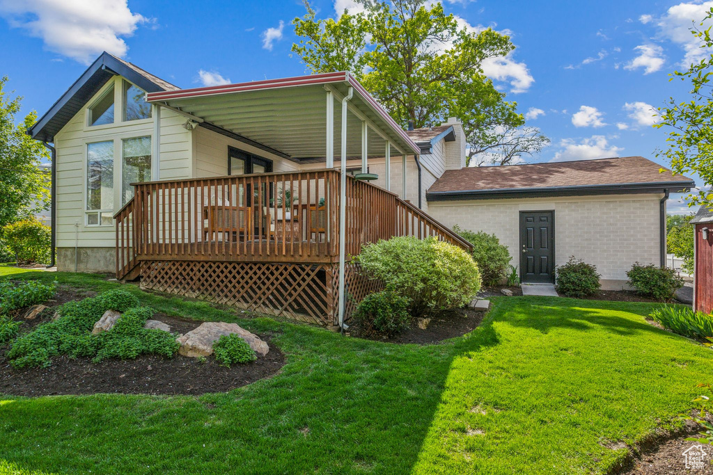 Back of house featuring a yard, a deck, and brick siding