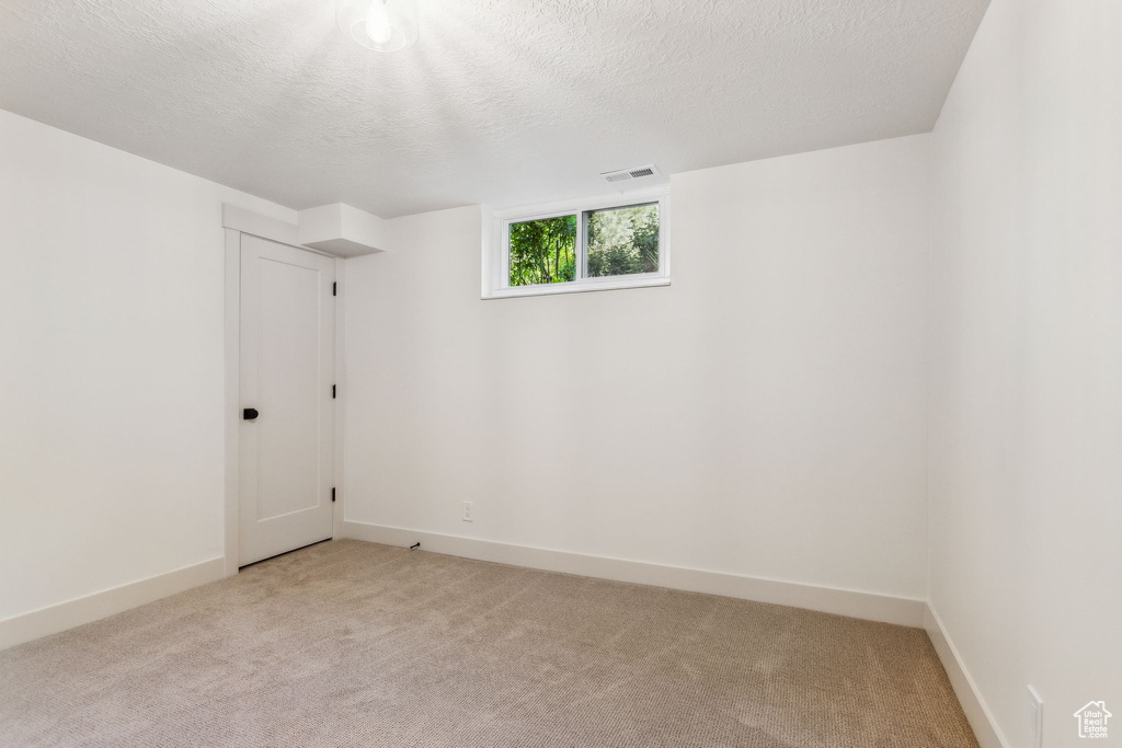 Unfurnished room with visible vents, a textured ceiling, baseboards, and light colored carpet