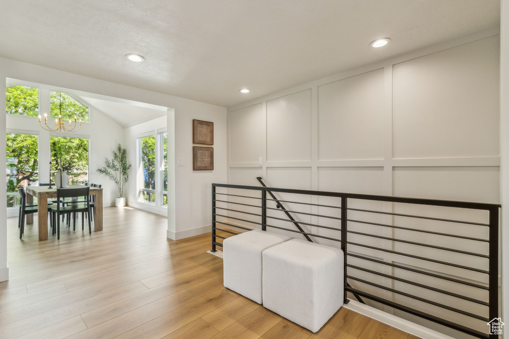 Living area with recessed lighting, a notable chandelier, lofted ceiling, and a decorative wall
