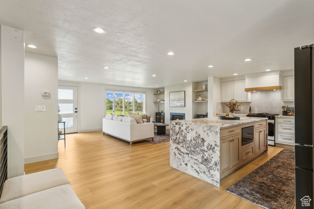Kitchen with built in microwave, high end stove, freestanding refrigerator, recessed lighting, and custom range hood