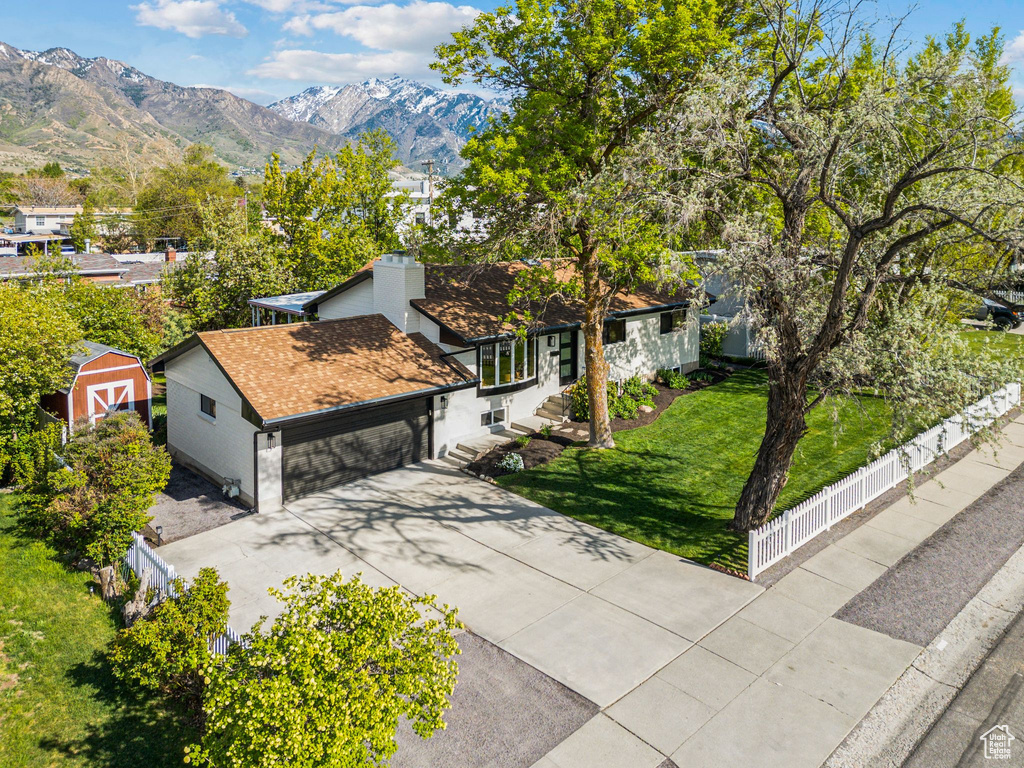 View of front of property featuring roof with shingles, a front yard, fence private yard, a garage, and concrete driveway