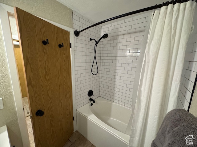 Full bathroom featuring a textured wall, tile patterned flooring, and shower / tub combo