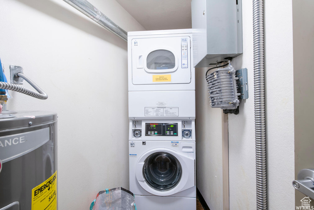 Washroom featuring laundry area, stacked washer and dryer, and electric water heater
