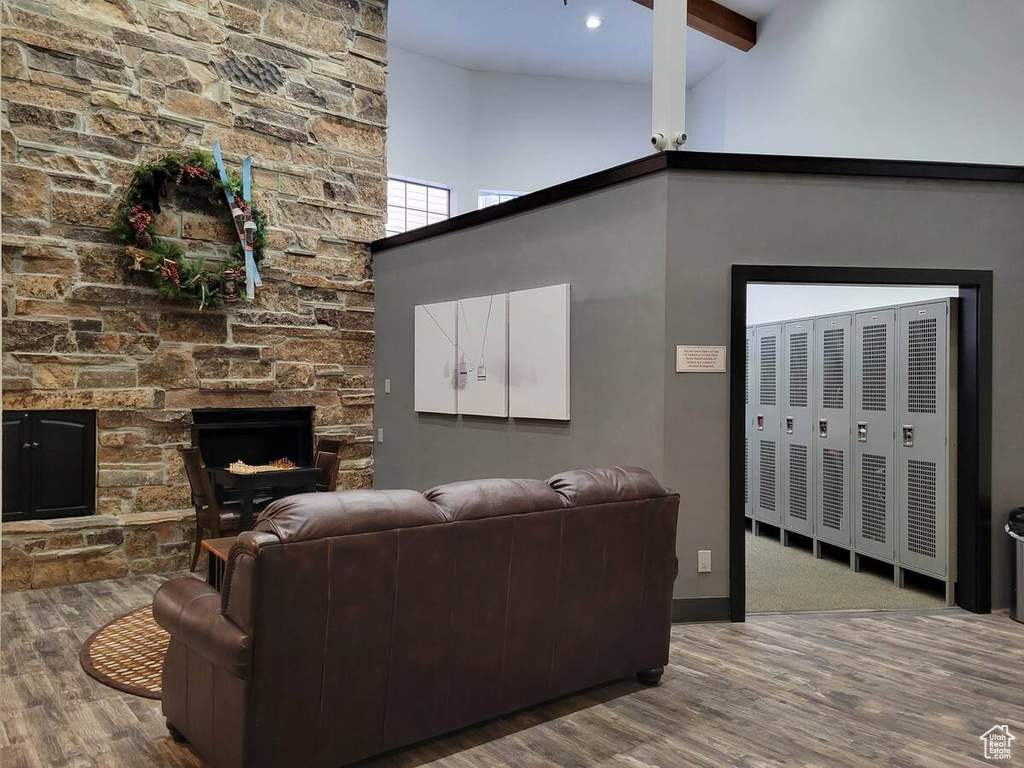 Living area with a high ceiling, a fireplace, baseboards, wood finished floors, and beamed ceiling
