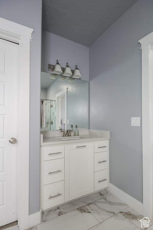 Bathroom with vanity, baseboards, a shower stall, and marble finish floor
